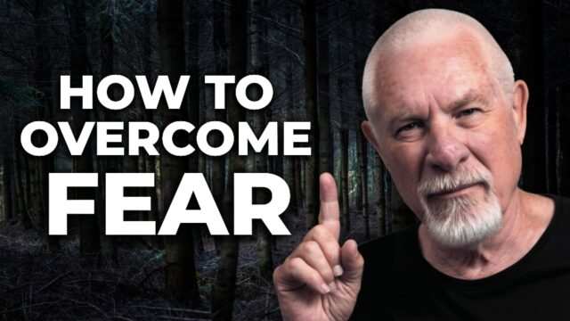 Vishrant, a silver-haired spiritual teacher, gestures calmly while pointing upward beside the words “How to Overcome Fear” on a dark background.